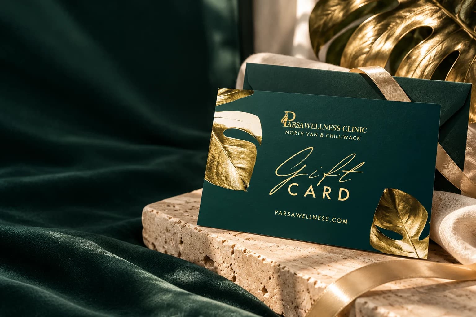 Parsa’s gold botanical gift card styled with a ribbon-wrapped envelope, travertine and linen
